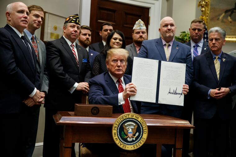 President Donald Trump shows off an executive order on a "National Roadmap to Empower Veterans and End Veteran Suicide," in the Roosevelt Room of the White House, Tuesday, March 5, 2019, in Washington.