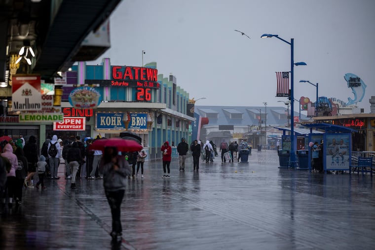 People walk on the Boardwalk during the heavy rainfall in Wildwood, N.J., on Saturday, May 23, 2026.