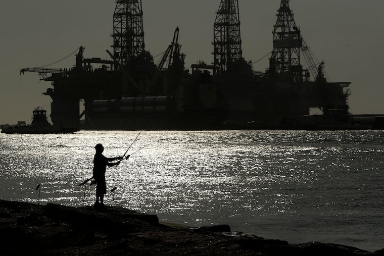 A man wears a face mark as he fishes near docked oil drilling platforms, on May 8, 2020, in Port Aransas, Texas. A federal court has rejected a proposed lease auction for offshore oil drilling in the Gulf of Mexico, saying the Biden administration failed to conduct a proper environmental review. The decision on Jan. 27, 2022, by U.S. District Judge Rudolph Contreras sends the proposed lease sale back to the Interior Department to decide next steps.