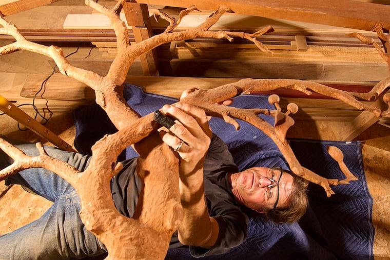 Sculptor Frank Seder Jr. lies on his back while he works in his Deptford studio. Seder, who is carving a staff for Pope Francis, previously created gifts for Pope Benedict XVI and Pope John Paul II. CHARLES FOX / Staff Photographer