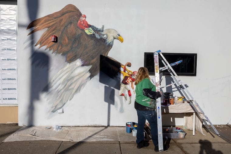 Philadephia muralist Artist Meg Saligman paints a mural of giant eagle with Kansas City football player Patrick Mahomes in its talons and coach Andy Reid riding on top.