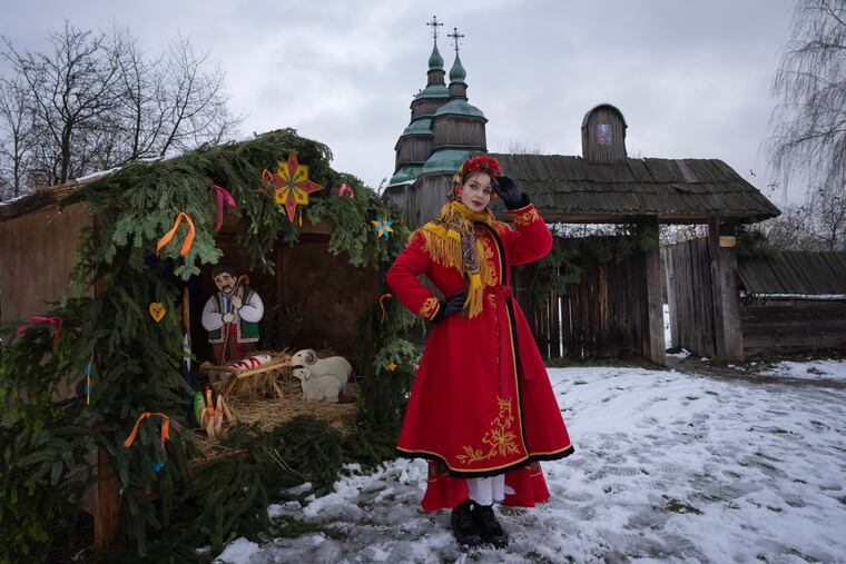 A woman dressed in national costume stands near the nativity scene to celebrate Christmas in the village of Pirogovo, outside the capital Kyiv, Ukraine, on Monday, Dec. 25, 2023.
