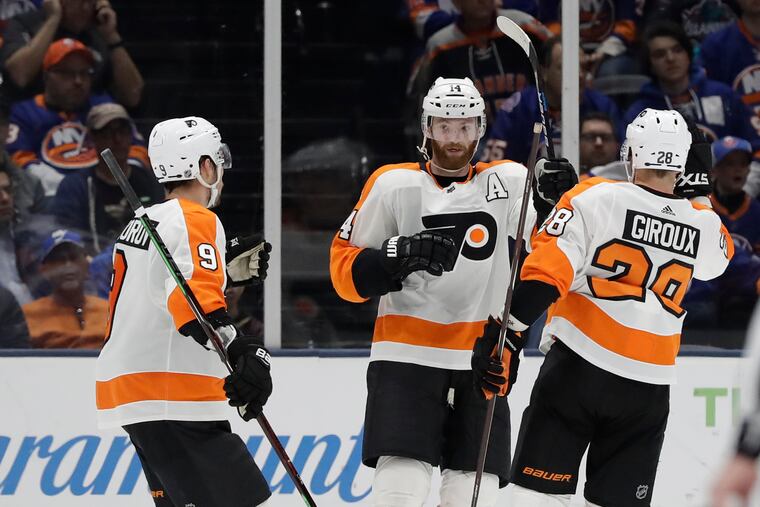 Ivan Provorov (9) and Claude Giroux celebrate with Sean Couturier (14), who scored the Flyers' fourth goal against the Islanders.