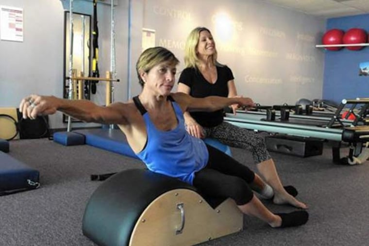 Delyn VanDyke, 52, who was hurt in a motorcycle crash in 2012, works to strengthen her body with trainer Tina Stathis, 48, at Tru Pilates and Yoga Studio in Altamonte Springs, Fla. Stathis is the owner. (Susan Jacobson/Orlando Sentinel/TNS)