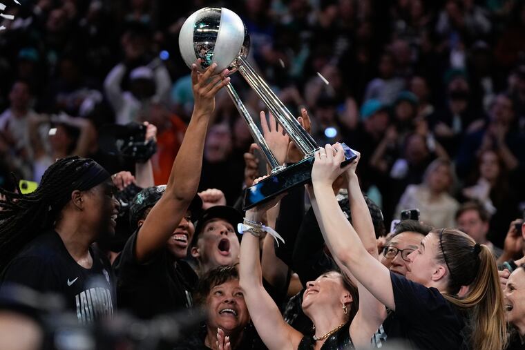New York Liberty players celebrate with the trophy after winning the team's long-awaited first WNBA title.