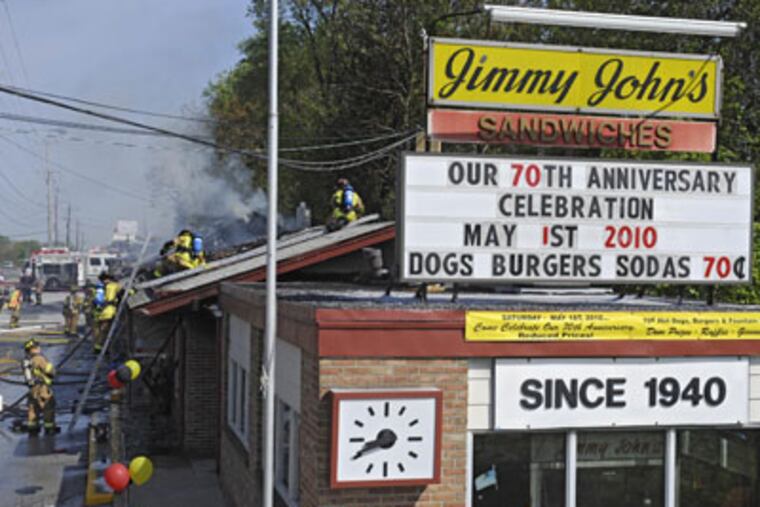 Firefighters swarm the roof of Jimmy John's, the landmark restaurant on Route 202 in Delaware County, which caught fire this morning as staff was getting ready to celebrate its 70th anniversary. ( Clem Murray / Staff Photographer )