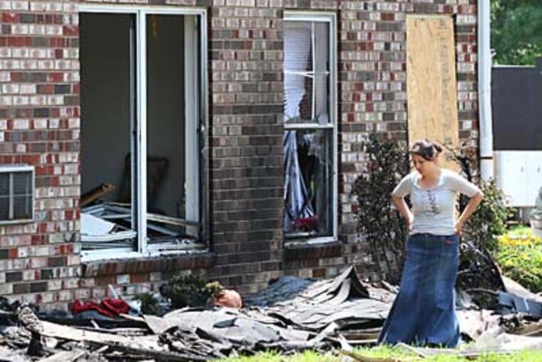 Raquel Sosa looks over the fire-damaged debris from her family's apartment unit at Gramercy Park apartments in Camden, NJ. A four-alarm fire during the night killed a toddler, injured 4 others, and destroyed 8 units. ( Charles Fox / Staff Photographer )