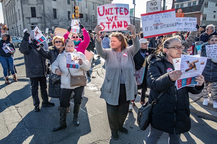 Ronnie Milillo, center, along with other South Philadelphia residents opposed to the proposed safe injection site, holds up her sign of protest to passing cars on South Broad Street in front of the proposed injection site at Constitution Health Plaza on March 1.