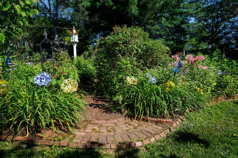 A sun garden at a home in Lansdale features plants, hardscaping, and glass ornaments.
