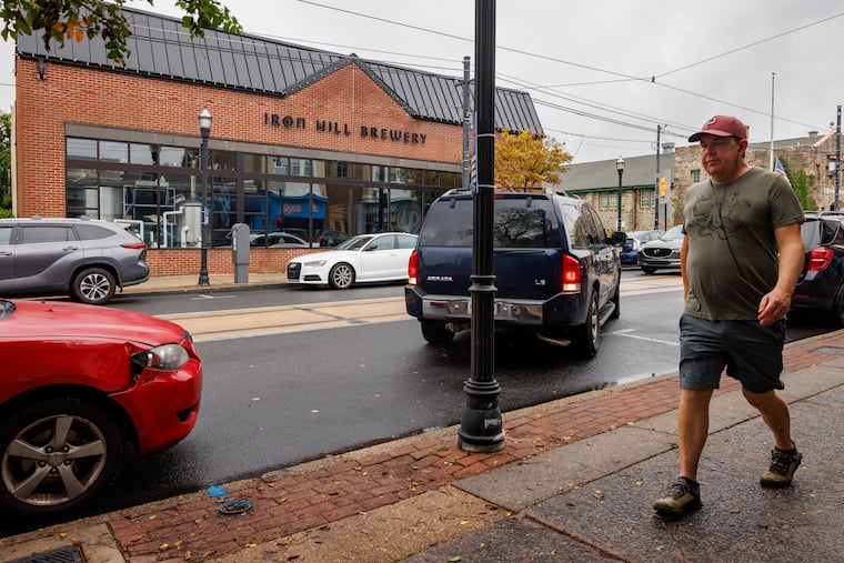 Scott Jillard walks past the shuttered Iron Hill Brewery on State Street in downtown Media. This restaurant and 15 other locations closed abruptly on Thursday.