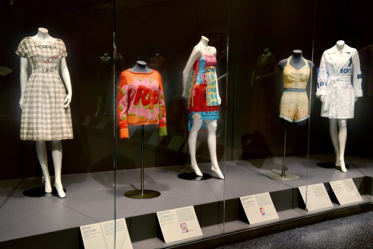 From the “Wear Words: Text in Fashion. On display (from left) are: “Woman's Dress,” Summer 1960, Designed by Tina Leser, American, 1910-1986, checked linen plain weave, flocked acrylic fiber /// “Woman's Sweater,” Mid-1990s, Iceberg a division of Gilmar, Milan, Wool, angora, and rayon knit with wool and alpaca knit appliqués and wool yarn /// "Woman’s Strapless Dress and Detachable Panel," 1998, Designed by Stephen Spouse, American, 1953-2004, printed silk satin, printed silk chiffon /// “Woman's Two-piece Swimsuit,” Mid- 1940s, artist/maker unknown, American, cellulose acetate plain weave printed on both sides /// and “Woman's Jacket and Belt," 2000-2009; Designed by Marian Schoettle, American, born 1954; White Tyvek (non-woven polyethylene) printed with red and blue. TOM GRALISH / Staff Photographer