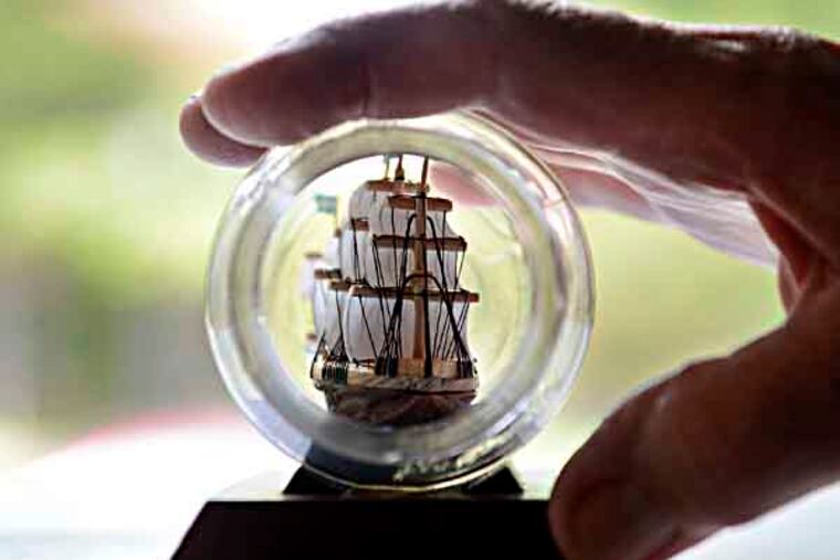 With a view looking through the glass jar opening, Joseph Ancona, a retired engineer's assistant who builds ships in bottles out of the shells of peanuts and other nuts, holds one of his creations at his Gloucester Twp. home September 26, 2013. ( TOM GRALISH / Staff Photographer )
