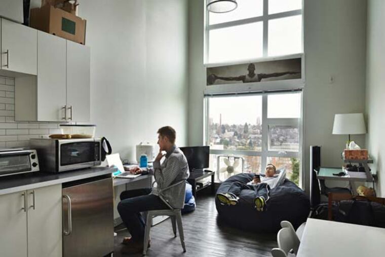 Seattle University student Brian Nguyen, right, reviews a recent tennis practice while his roommate, Cameron Hathaway, catches up on email. They say they get along well in their small space in Alder Flats near campus.(Benjamin Benschneider/Seattle Times/TNS)