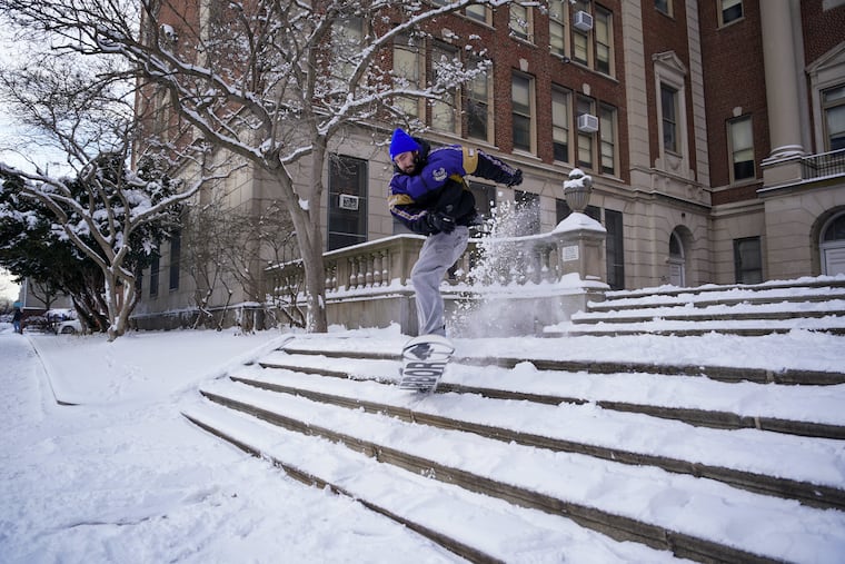 Someone snowboards down the steps of the Masterman school, on Spring Garden Street, in this 2022 file photo. Philadelphia schools will be closed Monday because of snow.