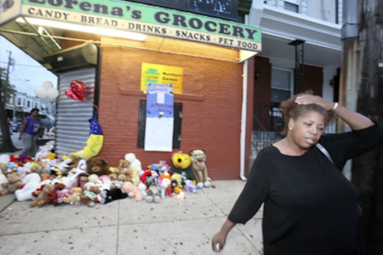 A mourner leaves after leaving a memento at the memorial outside Lorena's Grocery at 50th and Parrish, where three people were killed Tuesday. (Steven M. Falk / Staff Photographer)