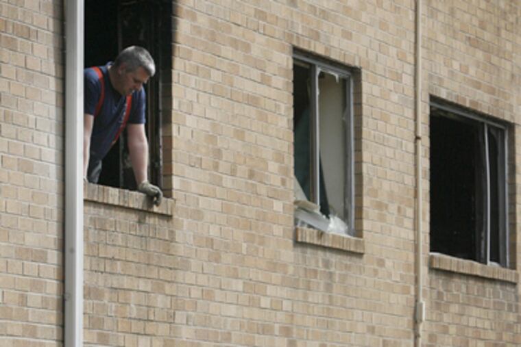 A fire investigator looks out at the debris after an apartment fire Tuesday at the Oxford House Apartments at 6451 Oxford Ave. in Northeast Philadelphia. (Alejandro A. Alvarez / Staff Photographer)