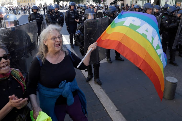 FILE - In this Saturday, March 23, 2019 file picture, anti-globalization activist Genevieve Legay, 73, demonstrates in front of riot police officers during a protest in Nice, southeastern France, as part of the 19th round of the yellow vests movement. French authorities are investigating the case of Genevieve Legay who suffered head injuries when police charged people defying a yellow vest protest ban in Nice. (AP Photo/Claude Paris, File)