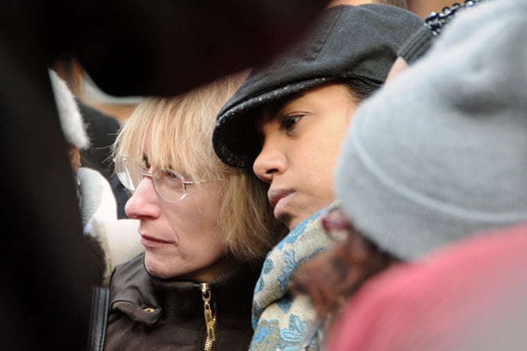 As they listen to a speaker, Stephanie Long, left, mother of Amber Long, who was murdered recently on Front St., gets a hug from Michelle Martin, owner of Urban Youth Racing School, near where Amber Long was killed. (Curt Hudson photo)
