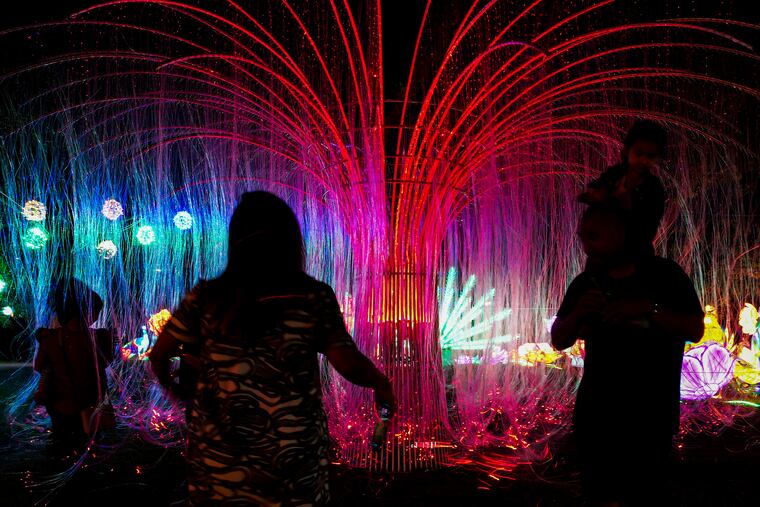 People interact with the Fairy Tale Tree at the Philadelphia Chinese Lantern Festival in Franklin Square on Tuesday, June 20, 2023. The festival is a celebration of light and culture that features steel-framed and silk-wrapped giant lighted sculptures, created by hand. The festival will run from June 21 to Aug. 13.
