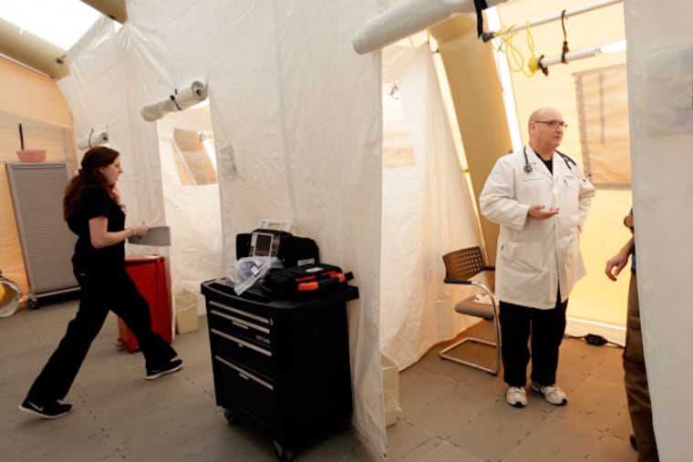 Registered nurse Michelle Newbury, left, and physician assistant Scott Fillman meet with patients, not pictured, in a tent set up for a people with flu symptoms, just outside the emergency entrance at the Lehigh Valley Hospital Thursday, Jan. 10, 2013, in Allentown, Pa. The Pennsylvania Department of Health designated flu as now "widespread" throughout the commonwealth. There have been more than 11,000 laboratory-confirmed flu cases in the state since the flu season began in mid-December. (AP Photo/Matt Rourke)