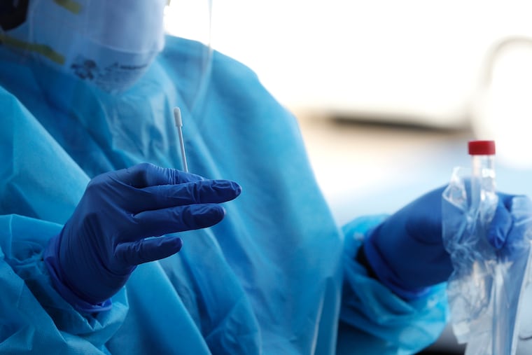 A nurse holds a nasopharyngeal swab (left) and the sample tube (right) during a coronavirus test in November.