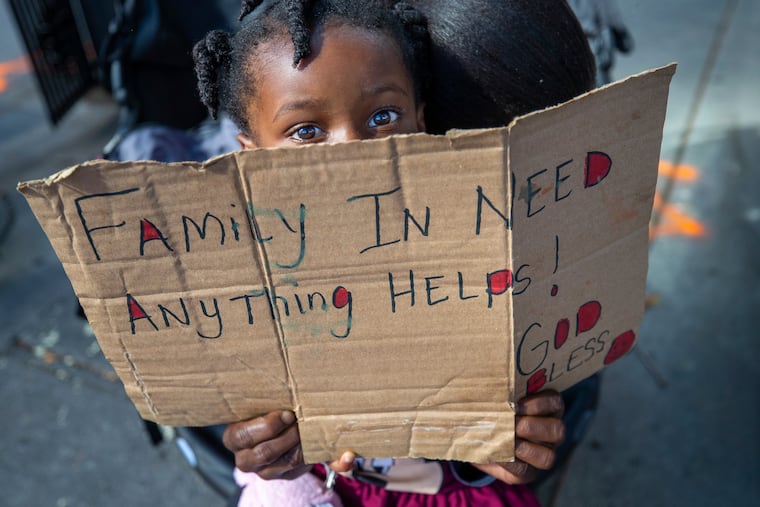 Nyla Clark, 3, accompanied by her mother, Chavonne Clark, sits in a baby stroller at a corner in New Orleans, hoping to get a few dollars from an occasional passerby Wednesday, March 25, 2020. Clark was a phlebotomist with a local company until she lost her job because of the coronavirus pandemic. She is waiting for unemployment. (David Grunfeld/The Advocate via AP)