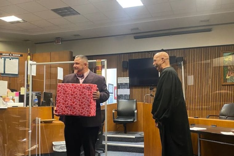 Edward Martell, left, holds a monogrammed briefcase given to him by his law firm after he was sworn in as a lawyer by Judge Bruce Morrow, his mentor.
