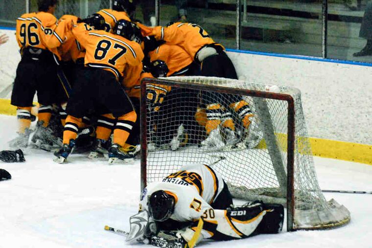 As Springfield players celebrate Billy McGugan's OT game-winner, Unionville goalie Christopher Sutera reacts. It was the Cougars' first Flyers Cup title since 2001.