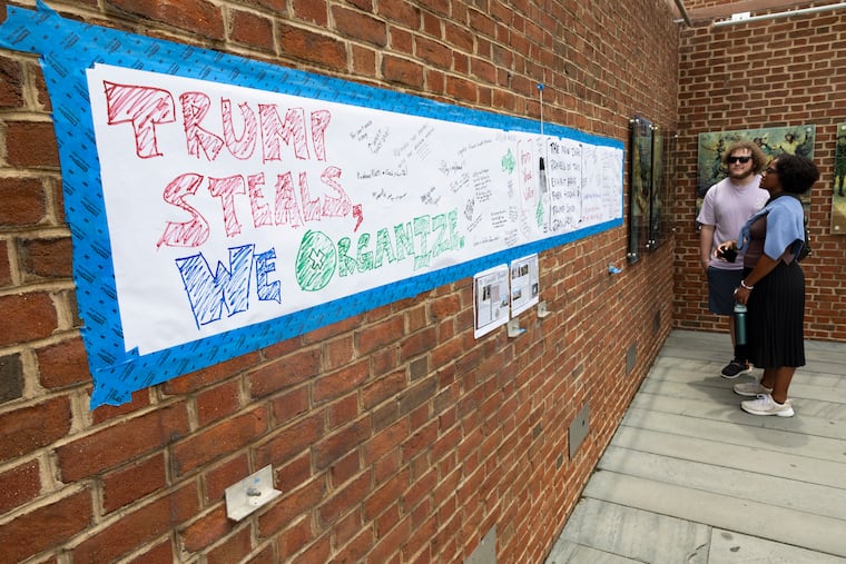 Visitors read the original panels at the President’s House alongside unofficial signage where visitors are encouraged to write down their reactions regarding the missing panels.