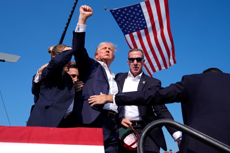 Republican presidential candidate and former President Donald Trump gestures as he is surrounded by U.S. Secret Service agents on stage at a campaign rally after what authorities are describing as an assassination attempt Saturday in Butler, Pa.
