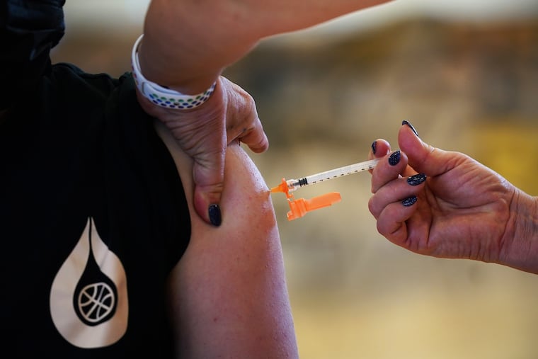 Nurse Kimball Dunlap (right) gives a first dose of the Pfizer COVID-19 vaccine to Jordan Rodriguez, 13, at a vaccination clinic for children 12 and older at Cheltenham High School in May.