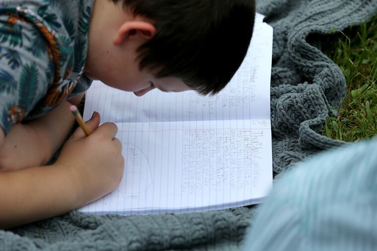 Sam Dukart, 9, works on a writing project during a homeschooling session his lawn in Cherry Hill, N.J. on Sept. 10. Elizabeth Dukart pulled her kids from Cherry Hill public schools to homeschool them during the pandemic.