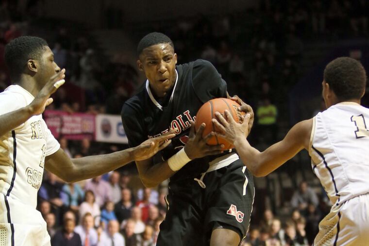 Carroll's Derrick Jones (center) holds the basketball against Neumann-Goretti's Jamal Custis (left) and Quade Green.