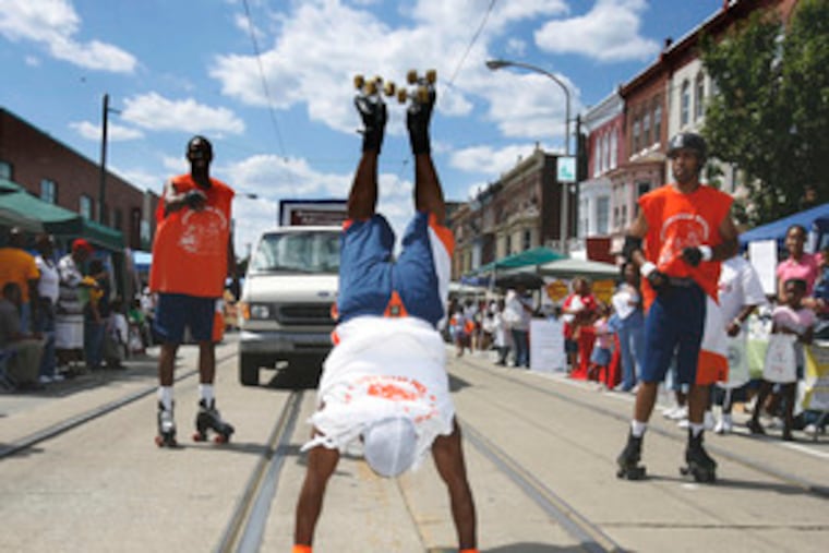 Wayne "Shorty" Morris goes upside down as he and other Wizards on Wheels perform on Baltimore Avenue at the 18th Neighborhood-to-Neighborhood Street Festival and parade.