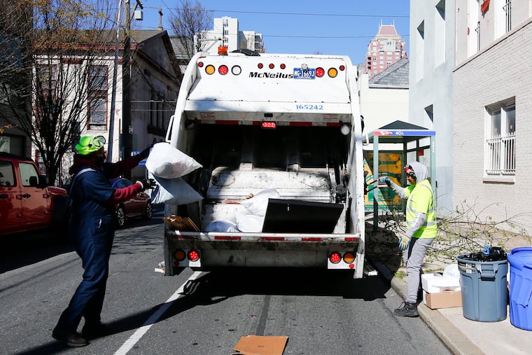 A City of Philadelphia sanitation worker tosses trash into a garbage truck along the 1100 block of Lombard Street.