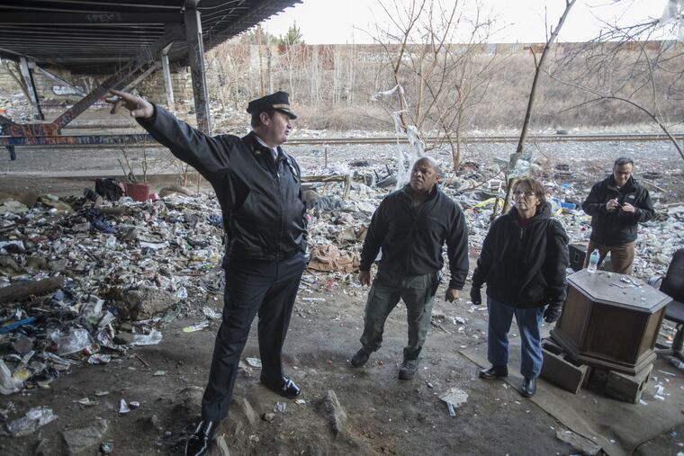 Philadelphia Police Inspector Michael McCarrick, left, points out areas where drug users will access the shooting gallery under the bridge at the the Conrail tracks in Fairhill. The city is now threatening to sue Conrail for not cleaning and sealing up the area.