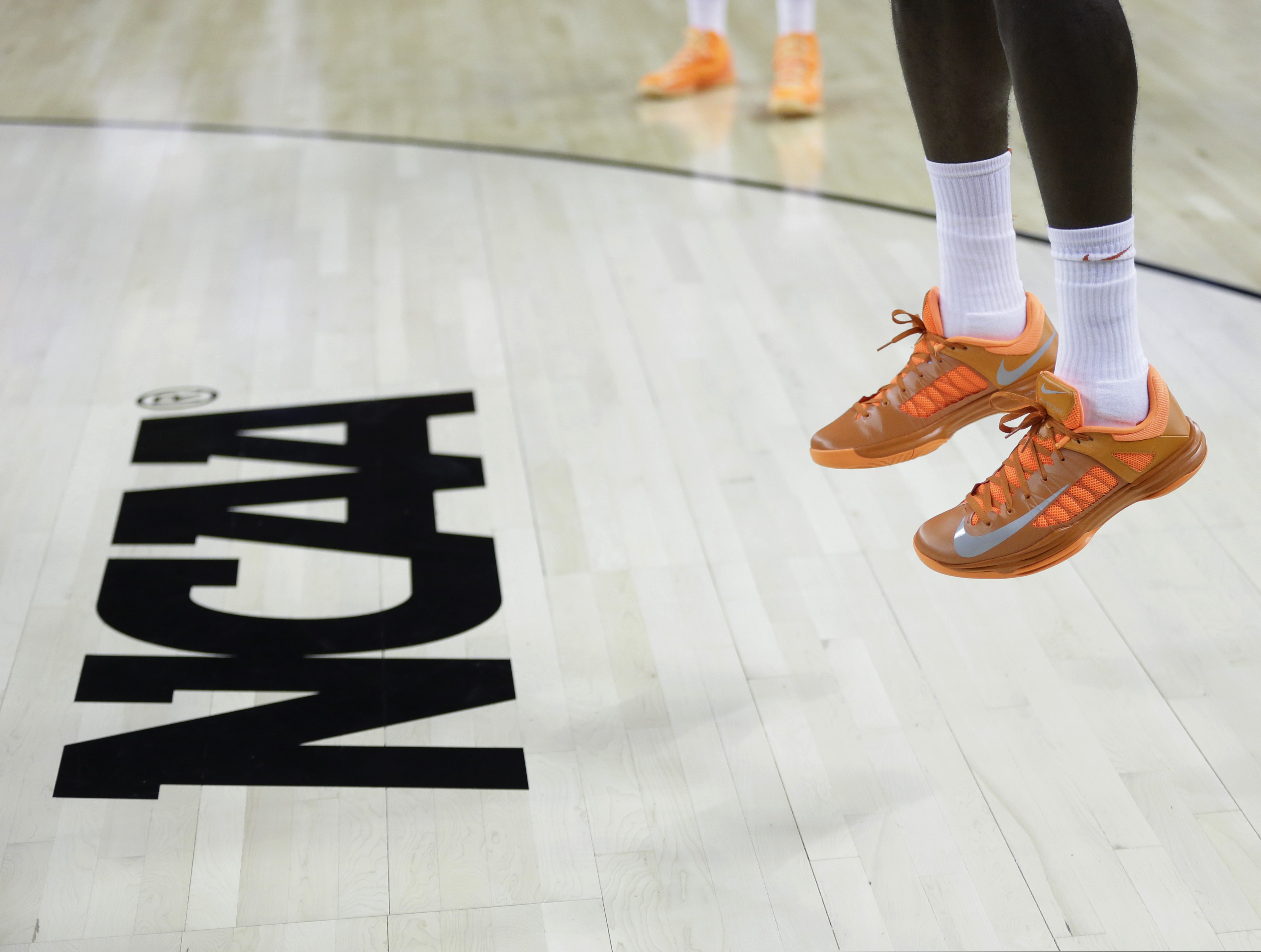In this March 21, 2013, file photo, an athlete jumps near the NCAA logo during practice for a second-round game of the NCAA college basketball tournament in Austin, Texas. California's governor signed a first-in-the-nation law Monday, Sept. 30 to let college athletes make money from endorsements, defying the NCAA — who then turned around last week and changed their policy.