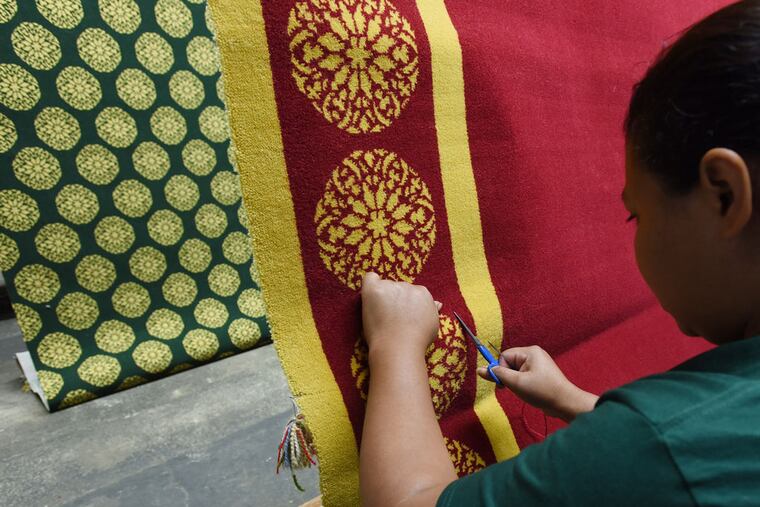 Carmen Martince does a quality control check and final inspection of the finished pope's red carpet at the Langhorne Carpet Company in Penndel. In the background is the green pope carpet, which will be installed in the pope's dressing room at the Cathedral Basilica of Saints Peter and Paul before he celebrates Mass on Sept. 27. (Philadelphia Inquirer/Bradley C Bower)