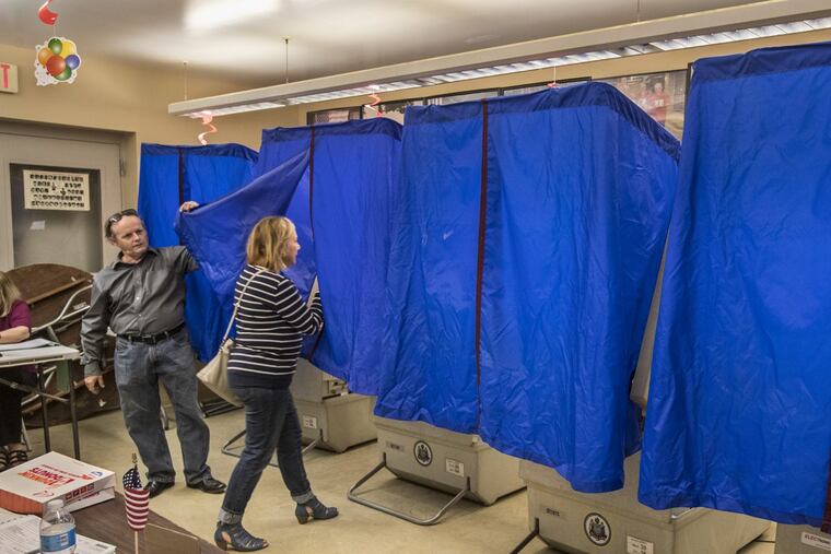 John Powell, left, the Judge of Elections for Ward 26, 4th Division, lets a voter enter the voting machine during the May 2017 primary.