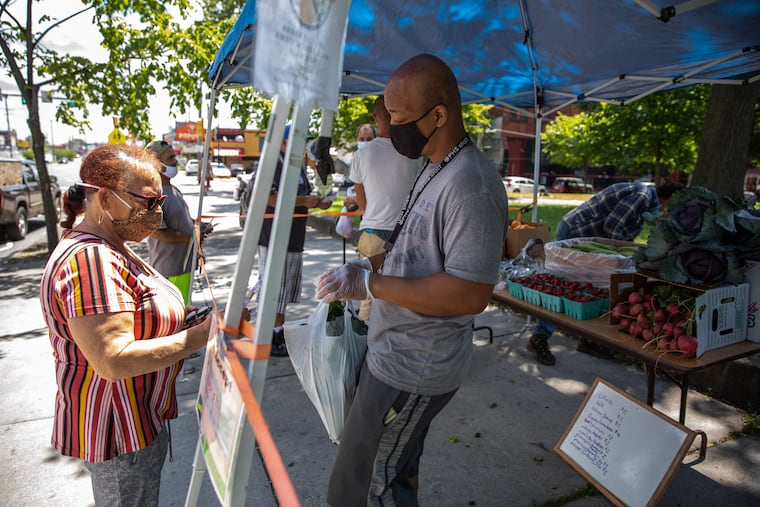Darnell Drayton (right) of DnD Farm talks with a shopper at 4th & Lehigh Farmers Market, part of The Food Trust's network of neighborhood markets that accept SNAP, WIC and Food Bucks.