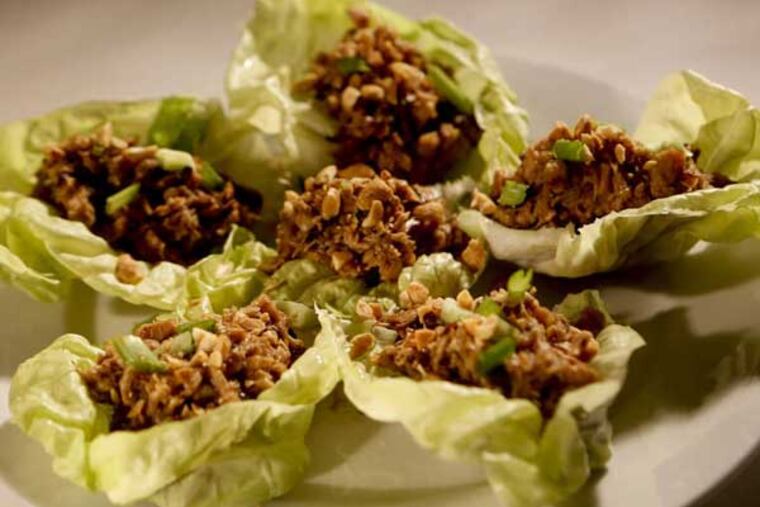 Cook rotisserie chicken with vegetables and spices, then serve in lettuce cups, with chopped roasted peanuts and green onion.