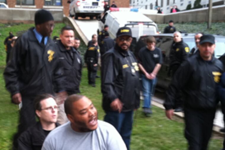 A handcuffed man being led into Family Court protested that police chose to "lock me up for restitution." He was among 22 arrested in city raids on the morning of Feb. 14, 2012.