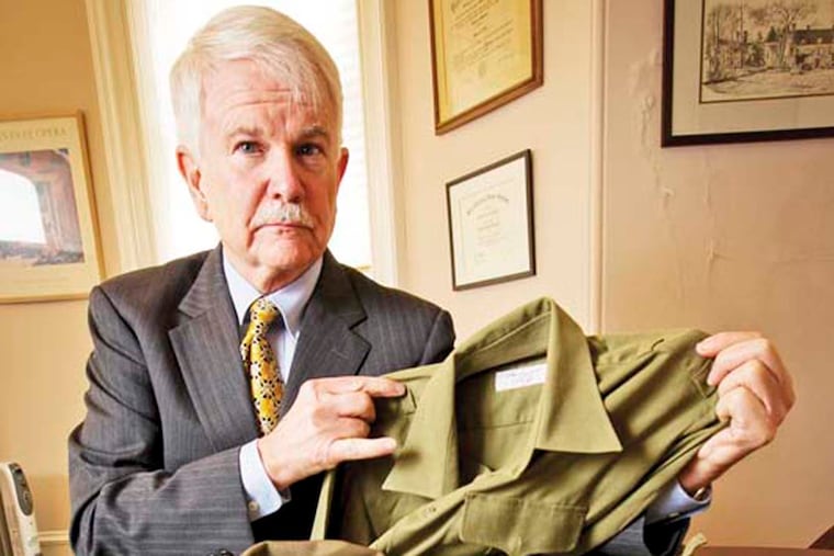 Dennis Murphy displays a North Vietnamese military uniform given to him by Thu Nguyen, the father of Rosemont student Phuong Nguyen.