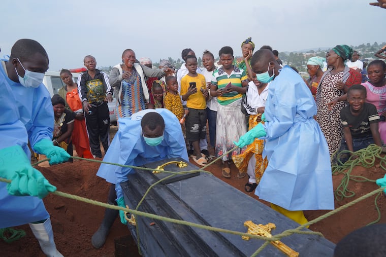 People dressed in protective gear lower into a grave the coffin containing the remains of Jeannine Katusabe, who died of Ebola, during a burial service Tuesday in Bunia, Ituri province, eastern Congo.