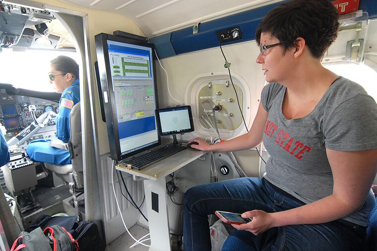 Mackenzie Smith (right), a post-doctorate research scientist from the University of Michigan, and pilots Kerryn Schneider (far left) and Shanae Coke (center) preparing for a flight in May. MARK NANCE / For The Inquirer
