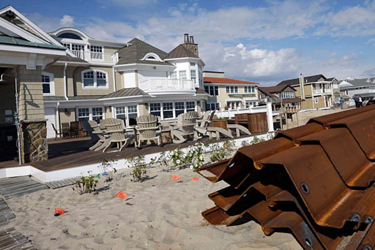 Mantoloking homes that have been restored after Hurricane Sandy rise behind long steel sheets that will be driven into the dunes to make a protective barrier as part of Shore restoration. (Mel Evans/Staff)