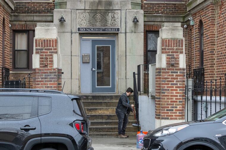 A man cleans the steps outside a property on North 12th Street early Thursday morning at the scene of a fatal overnight shooting.