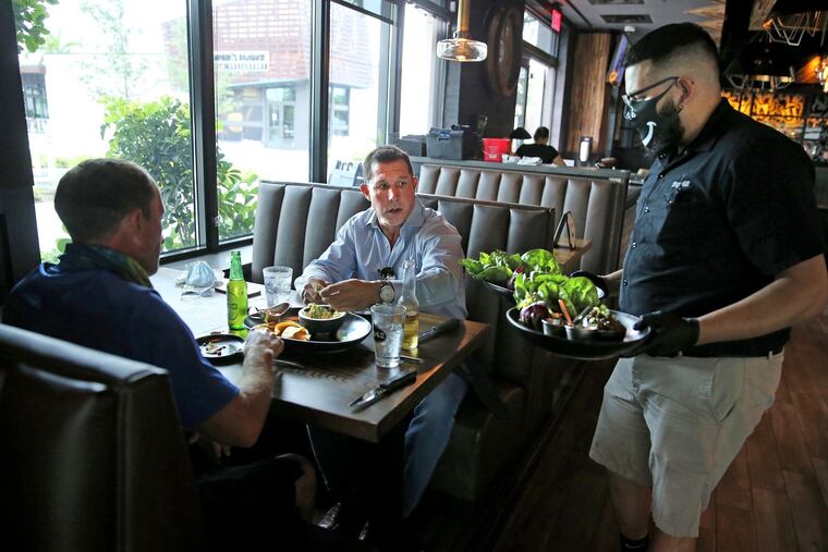 DJ Darcello is the first to order food at Tap42 Doral at City Place after the coronavirus closed the restaurant industry and other businesses, May 18, 2020. Today is the first day restaurants could open at 50 percent capacity. (Charles Trainor Jr./Miami Herald/TNS)