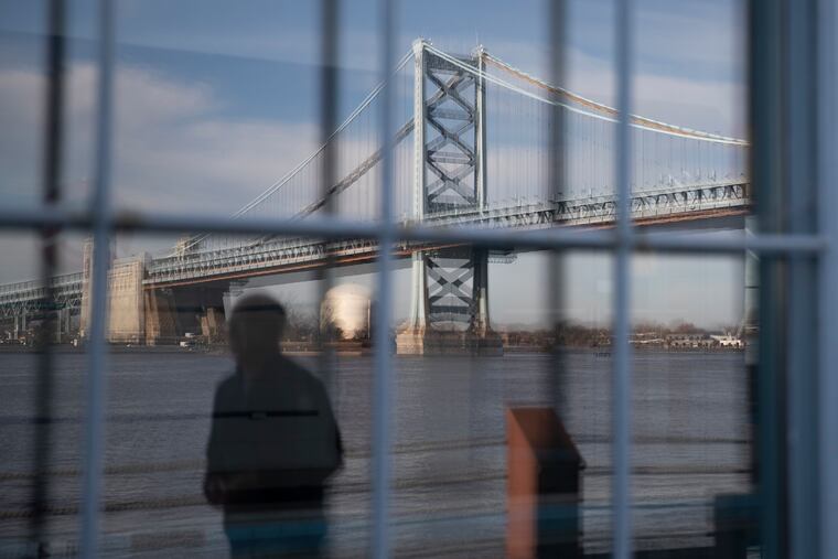 Homeowner Steve Peikin is reflected in the large windows of the Pier 3 Condominium building along with the Ben Franklin Bridge in Philadelphia on Thursday, Dec. 03, 2020.