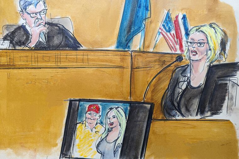 In this courtroom sketch, Stormy Daniels testifies on the witness stand as Judge Juan Merchan looks on in Manhattan criminal court Tuesday. A photo of Donald Trump and Daniels from their first meeting is displayed on a monitor.
